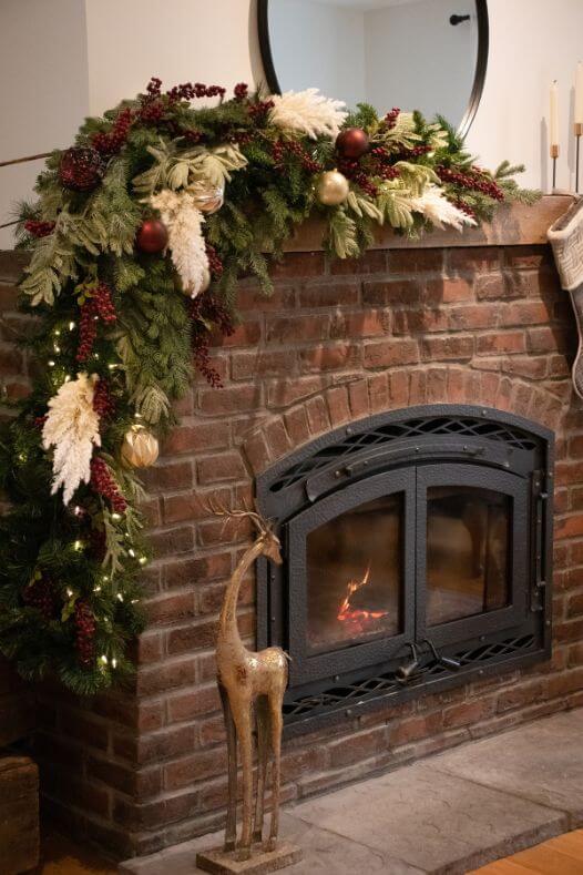 Guirlande de Noël avec pampas sur manteau de foyer en brique rouge - Décors Véronneau