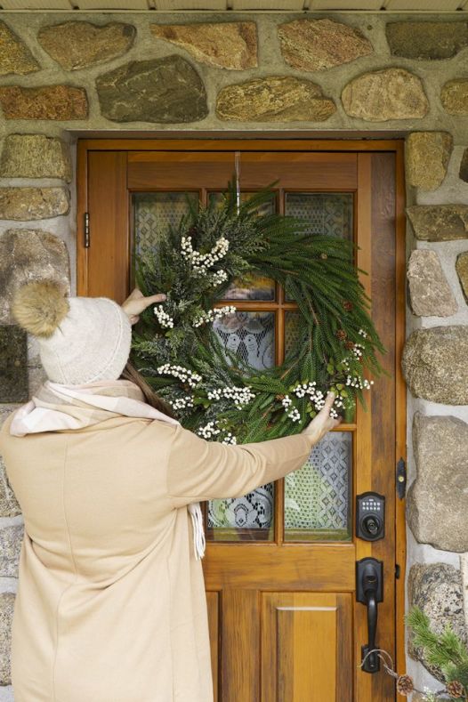 Installation d'une couronne de Noël hivernale sur porte en bois - Décors Véronneau
