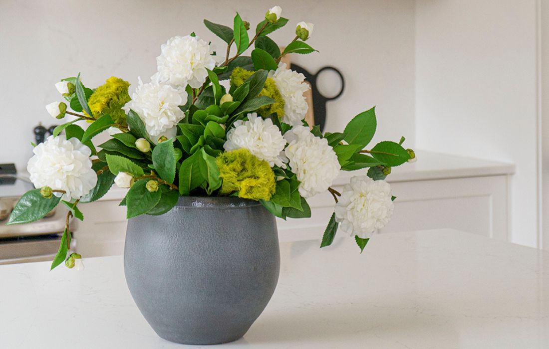 Arrangement floral artificiel vert et blanc dans un pot gris sur comptoir de cuisine - Décors Véronneau
