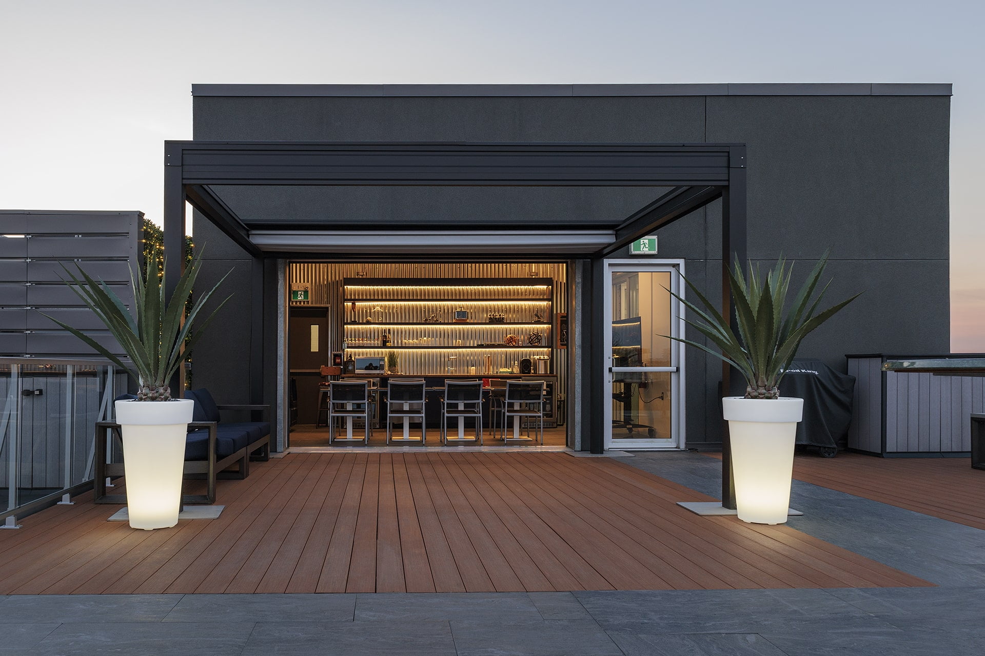 Bar sur terrasse avec agaves artificiels en pots blancs éclairés. - Décors Véronneau