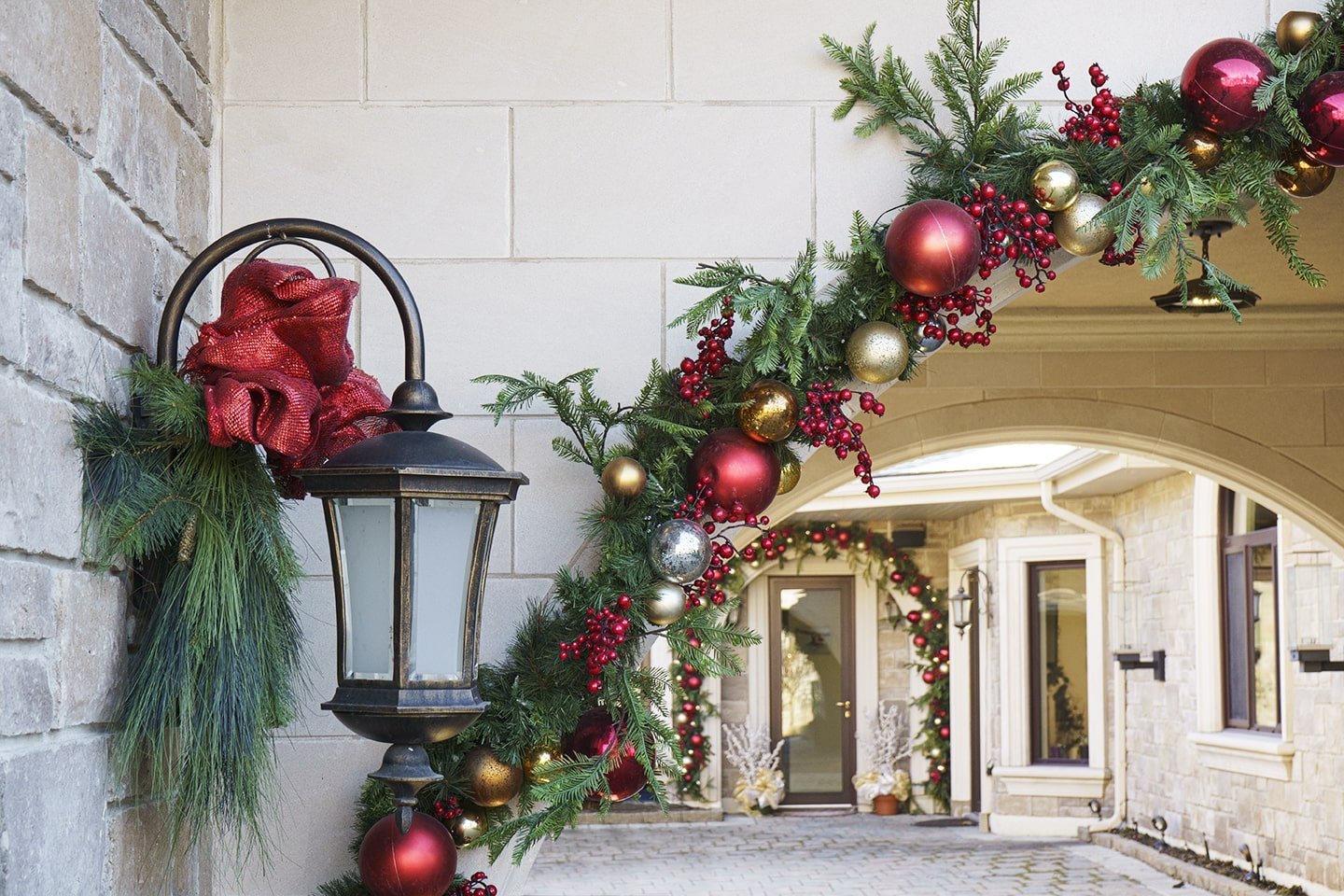 Guirlande de Noël décorée de boules de Noël sur une arche extérieure - Décors Véronneau