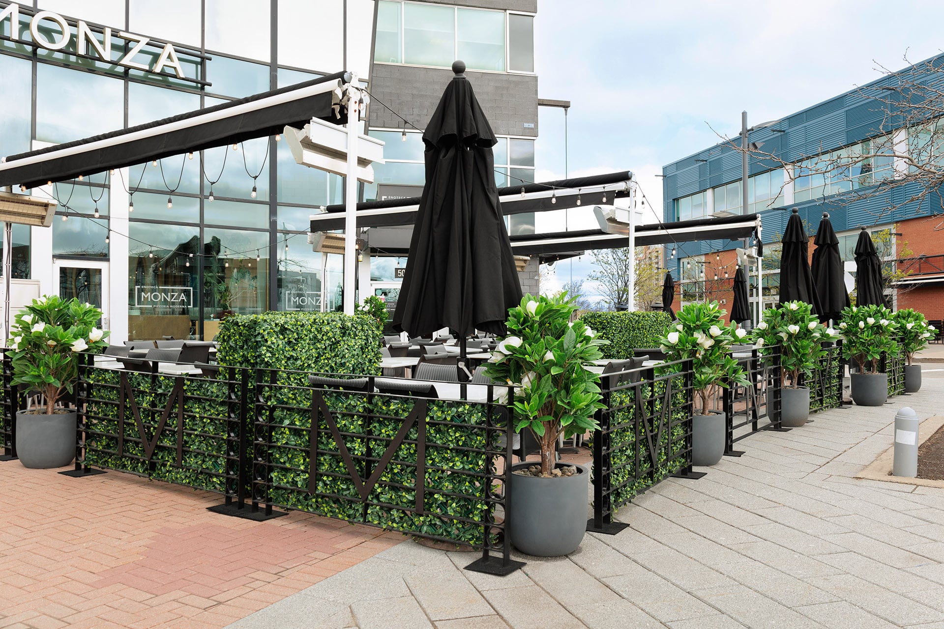 Ajout de panneaux de treillis installé sur les clôtures pour créer de l'intimité à la terrasse. Haies de buis artificielles jouant le rôle de division entre les tables du restaurant. - Décors Véronneau