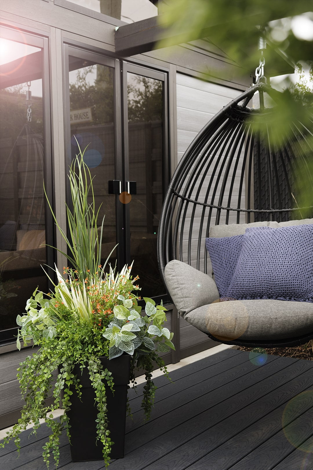 Jardinière de sol artificielle à côté d'une chaise suspendue. - Décors Véronneau