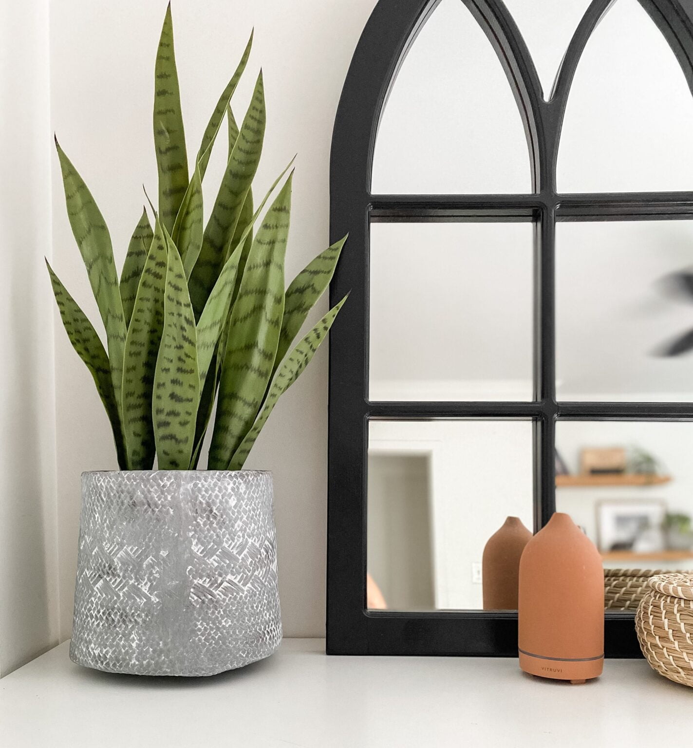 Fausse sansevière artificielle sur une commode blanche avec miroir noir - Décors Véronneau
