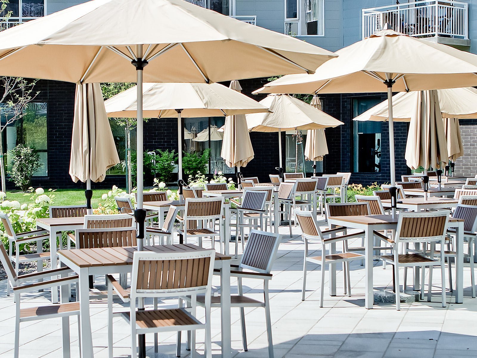 Terrasse ensoleillée, ornée de parasols, tables et chaises haut de gammes - Décors Véronneau
