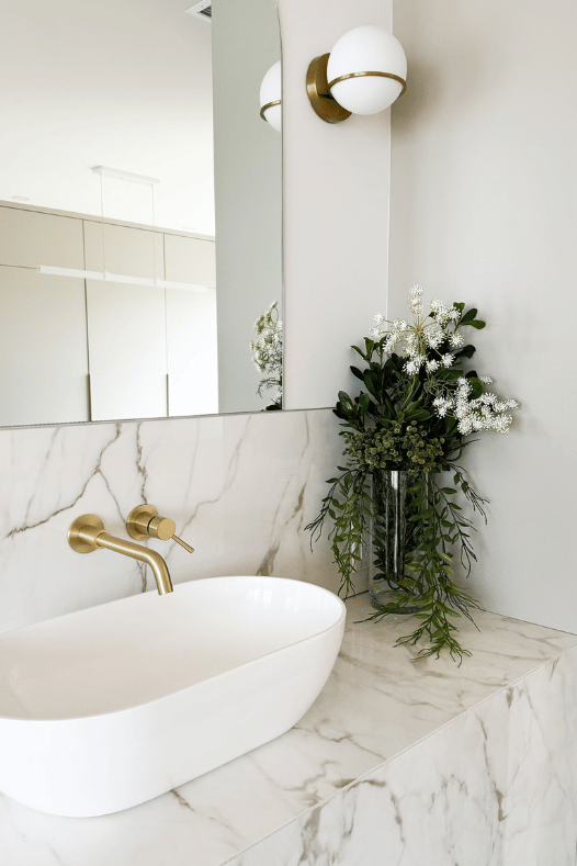 Vanité avec comptoir en marbre et fleurs dans une salle de bain - Décors Véronneau