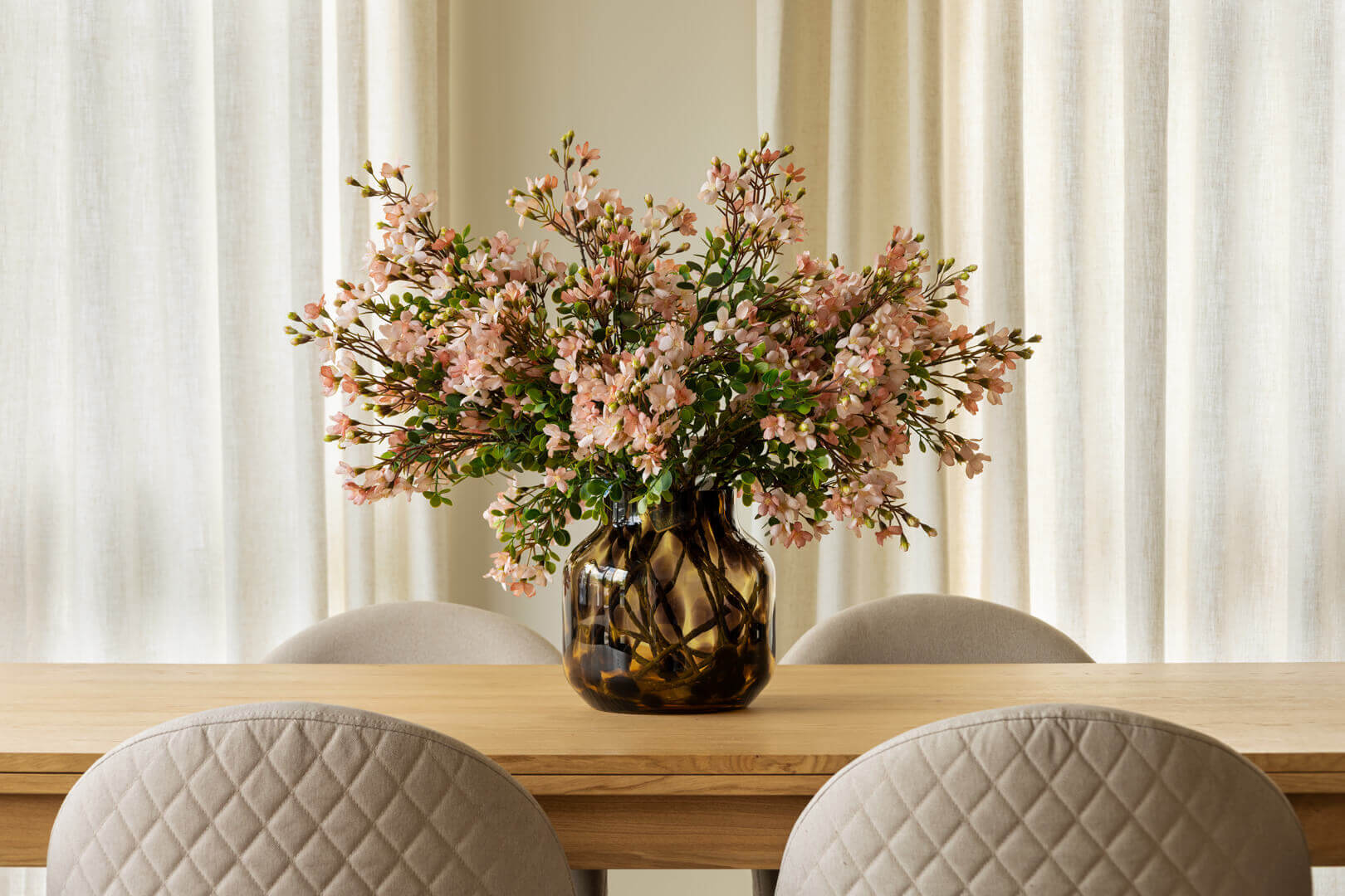 Bouquet de fleurs artificielles de cerisier rose dans un vase en verre sur une table - Décors Véronneau