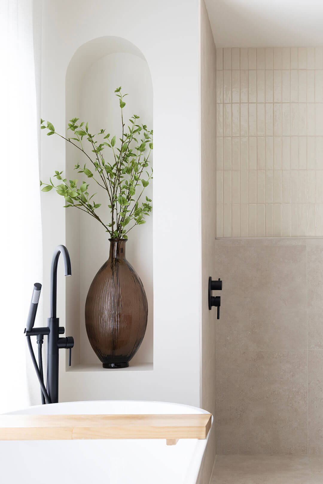 Vase en verre avec feuillage artificiel dans une arche décorative de salle de bain - Décors Véronneau