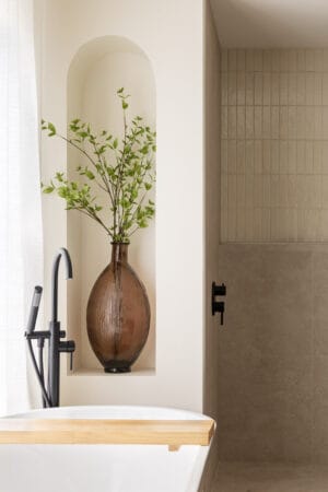 A vase of greenery in a bathroom wall niche